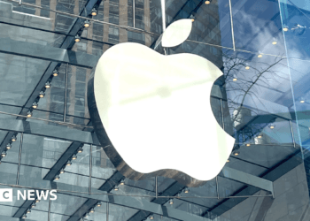 The apple logo on a clear round store is visible in amongst the skyscrapers in a city