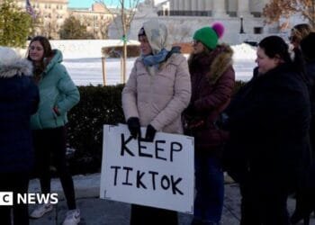 A group of young people holding a sign reading 'Keep TikTok' stand in cold-weather clothes outside the Supreme Court in the US.