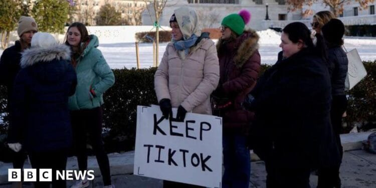 A group of young people holding a sign reading 'Keep TikTok' stand in cold-weather clothes outside the Supreme Court in the US.