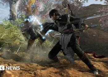 A character attacks another, causing him to fly backwards with light refracting off his body. They are both dressed in feudal era Chinese clothes and wielding swords. Behind them, a lush green scene with cherry blossom trees.
